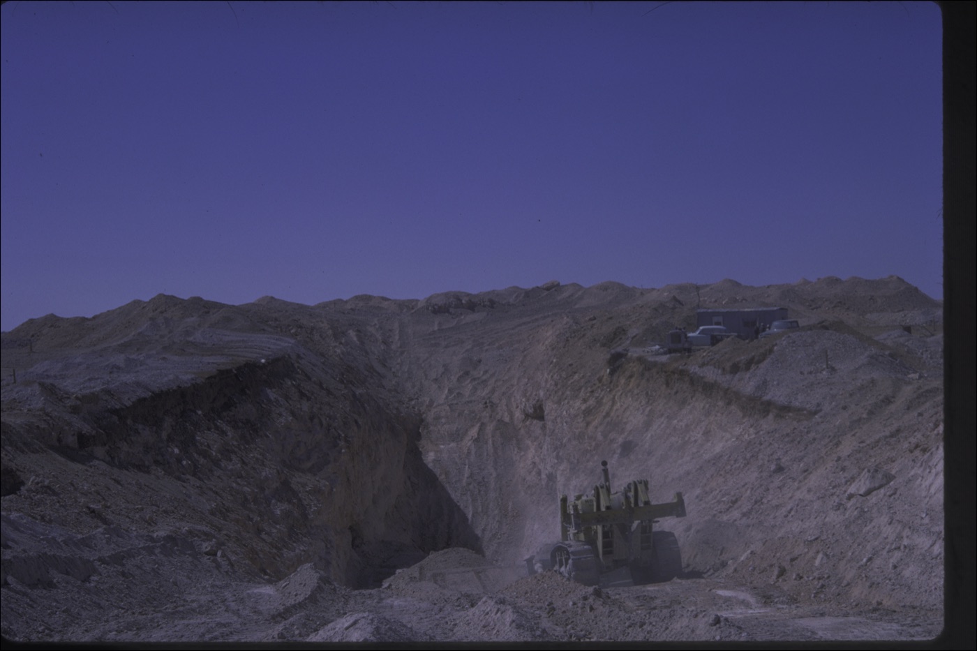 The hired bulldozer working an open cut at the Ten Mile field, Coober Pedy, with the camp on the rim